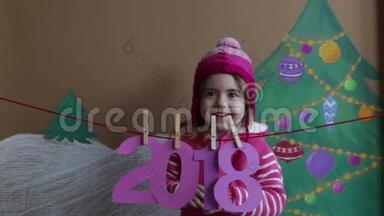 新年2018概念。 美丽的小女孩装饰新年数字。 一棵彩绘圣诞树的背景